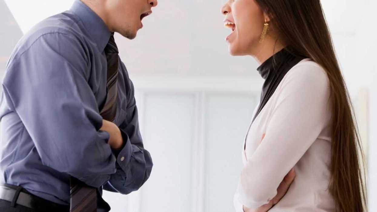 A man and woman squabble face to face at work