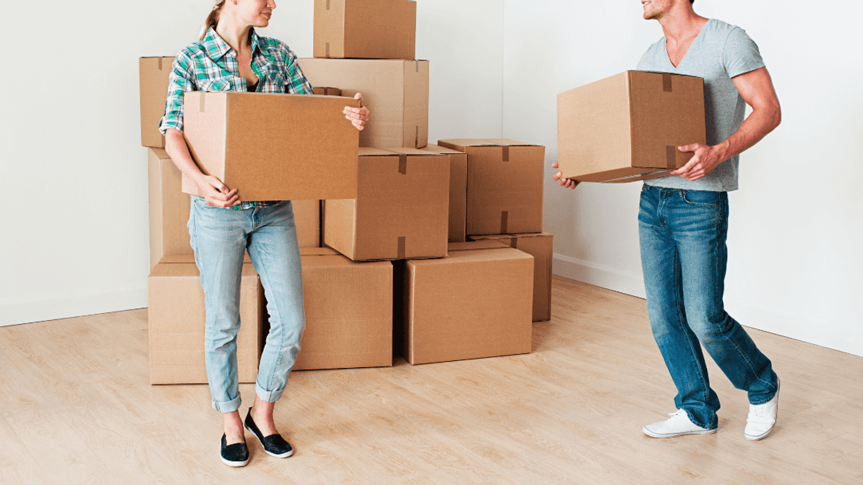 A man and woman with moving boxes in their arms and on the floor.