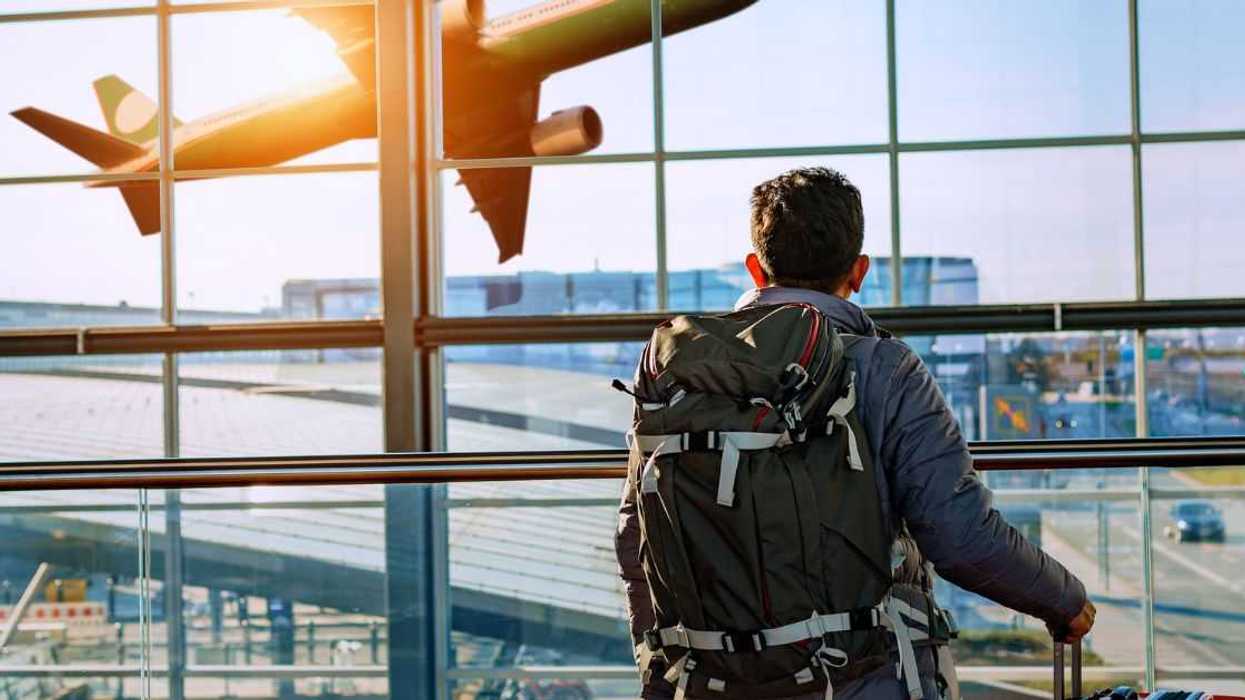 A man at the airport watches a plane leave