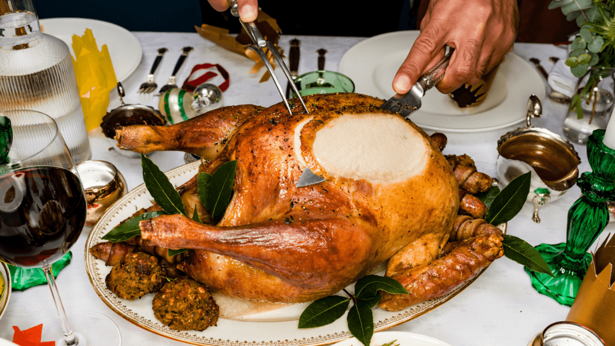 A man carving a turkey on a Thanksgiving table.