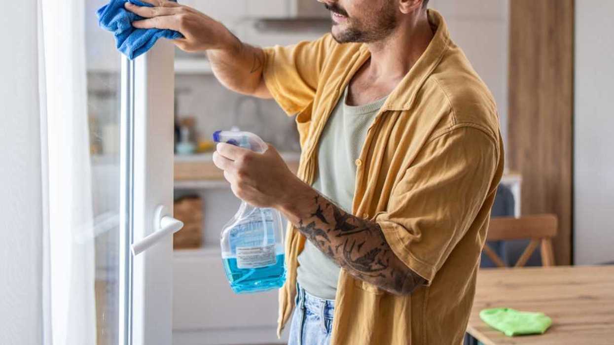 A man cleaning windows at home, ensuring a clear and fresh view. This scene emphasizes the importance of home maintenance and creating a tidy, pleasant living environment.