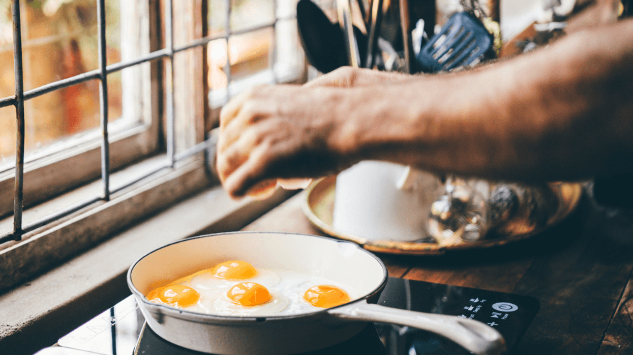 A man cooking eggs om a stoveop.