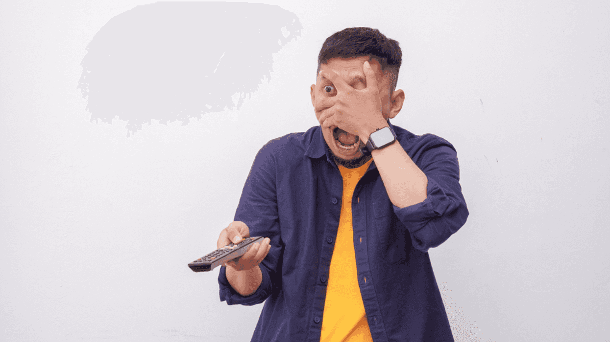 A man covering his eyes holding a remote control.