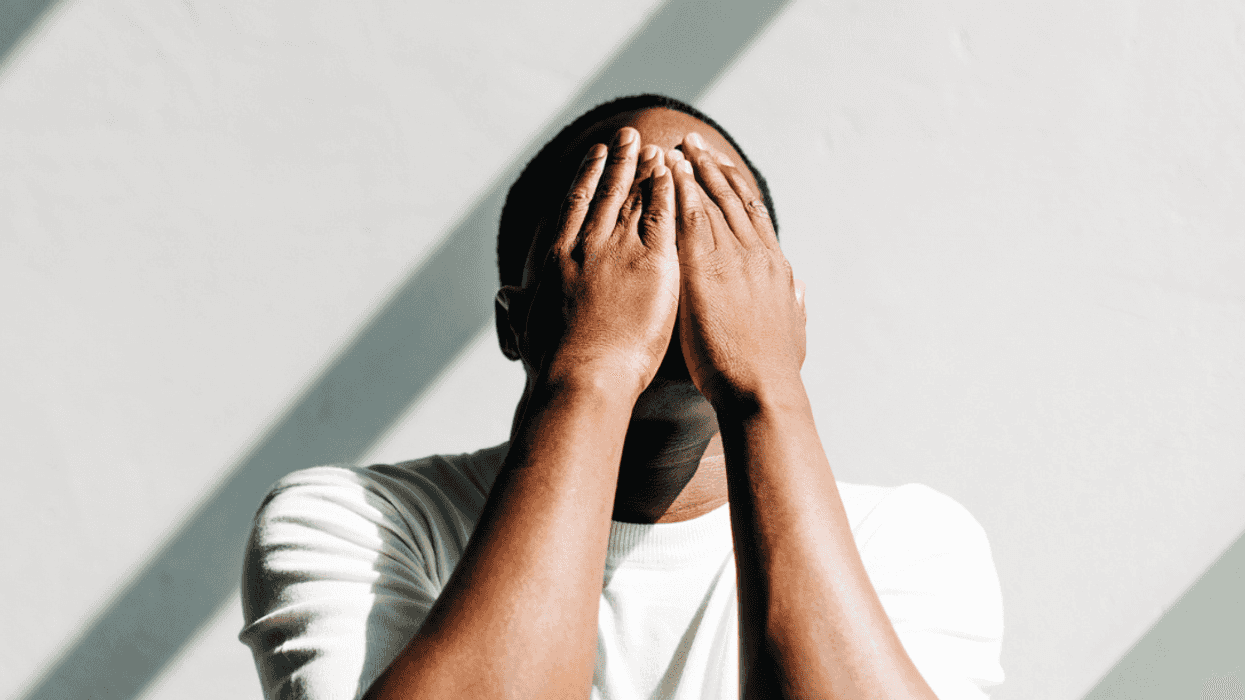A man covering his face with his hands.