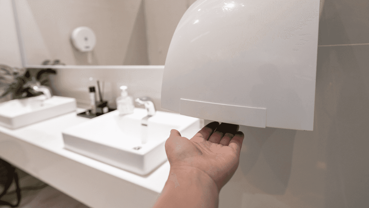 A man drying his hands under an electric handr