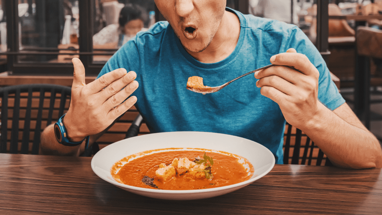 A man eating a spicy bowl of soup.