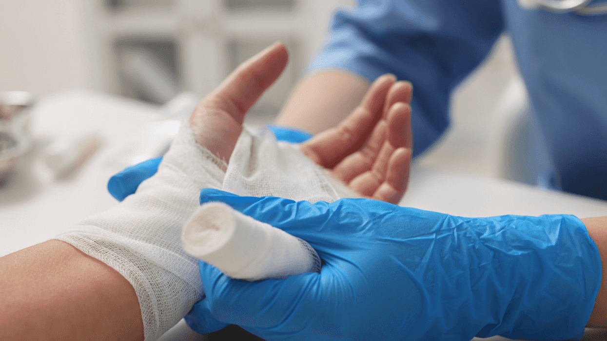 A man getting his hand wrapped in gauze