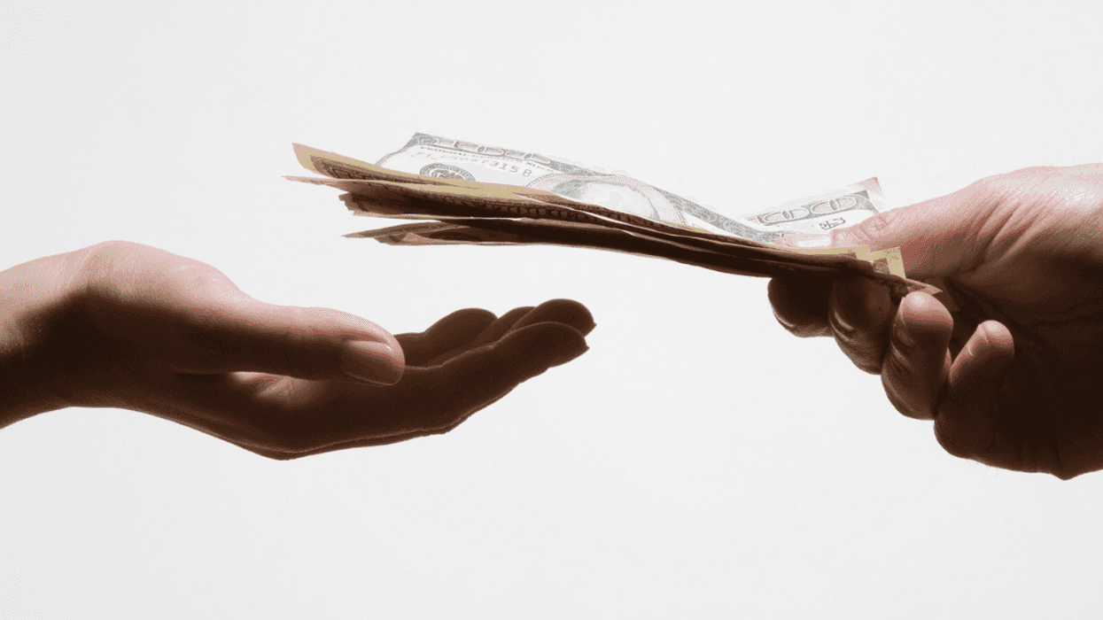 A man handing a woman a pile of cash.