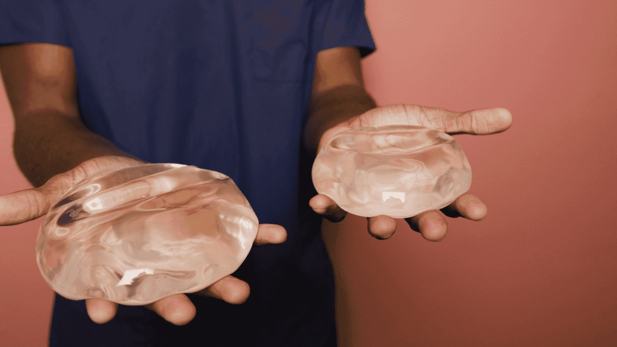 A man holding a breast implant in each hand.