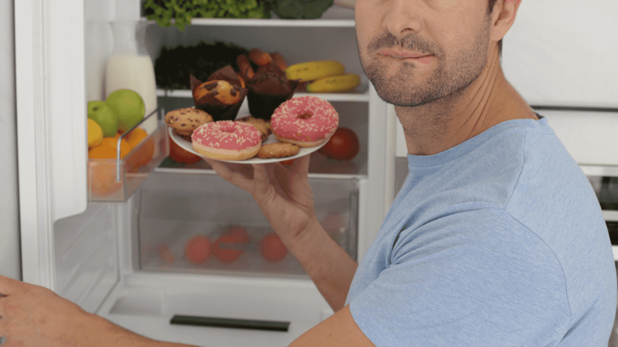 A man holding a plate of pastries in front of a refrigerator