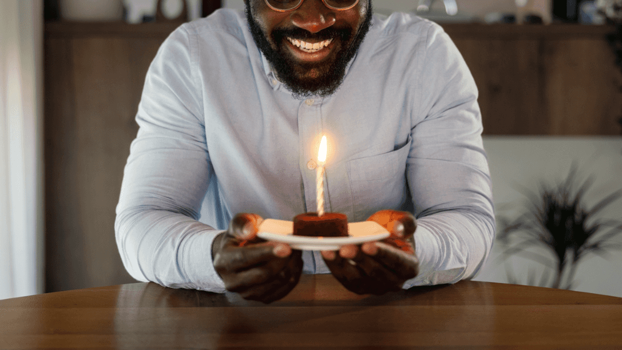A man holding a plate with a candle in it.