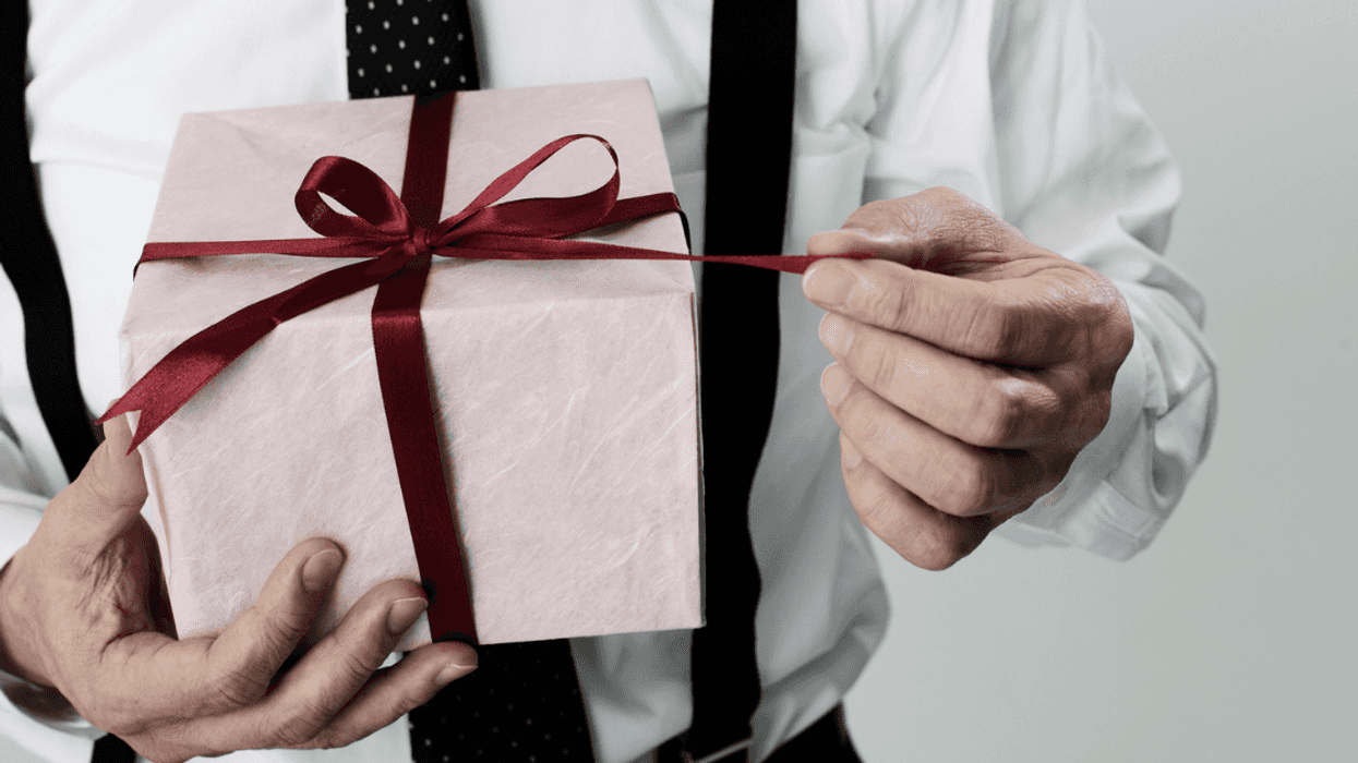A man holding a present pulling on the ribbon.