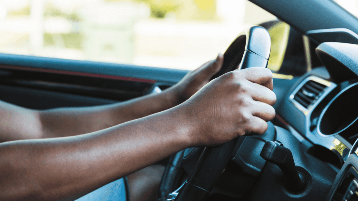 A man holding the steering wheel of a car.