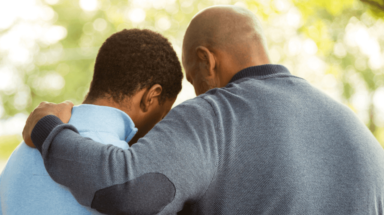 A man hugging his son with their backs to the camera.