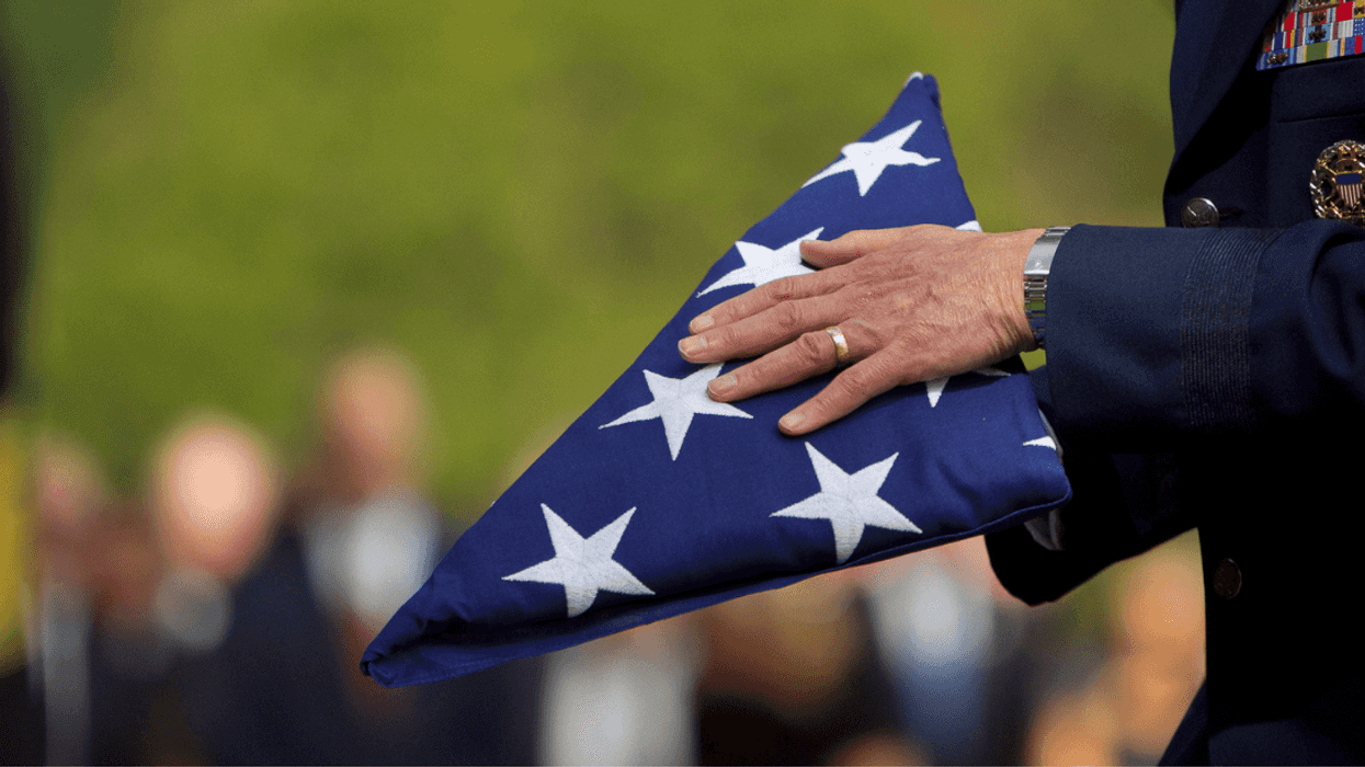 A man in a military uniform holding a folded American flag.