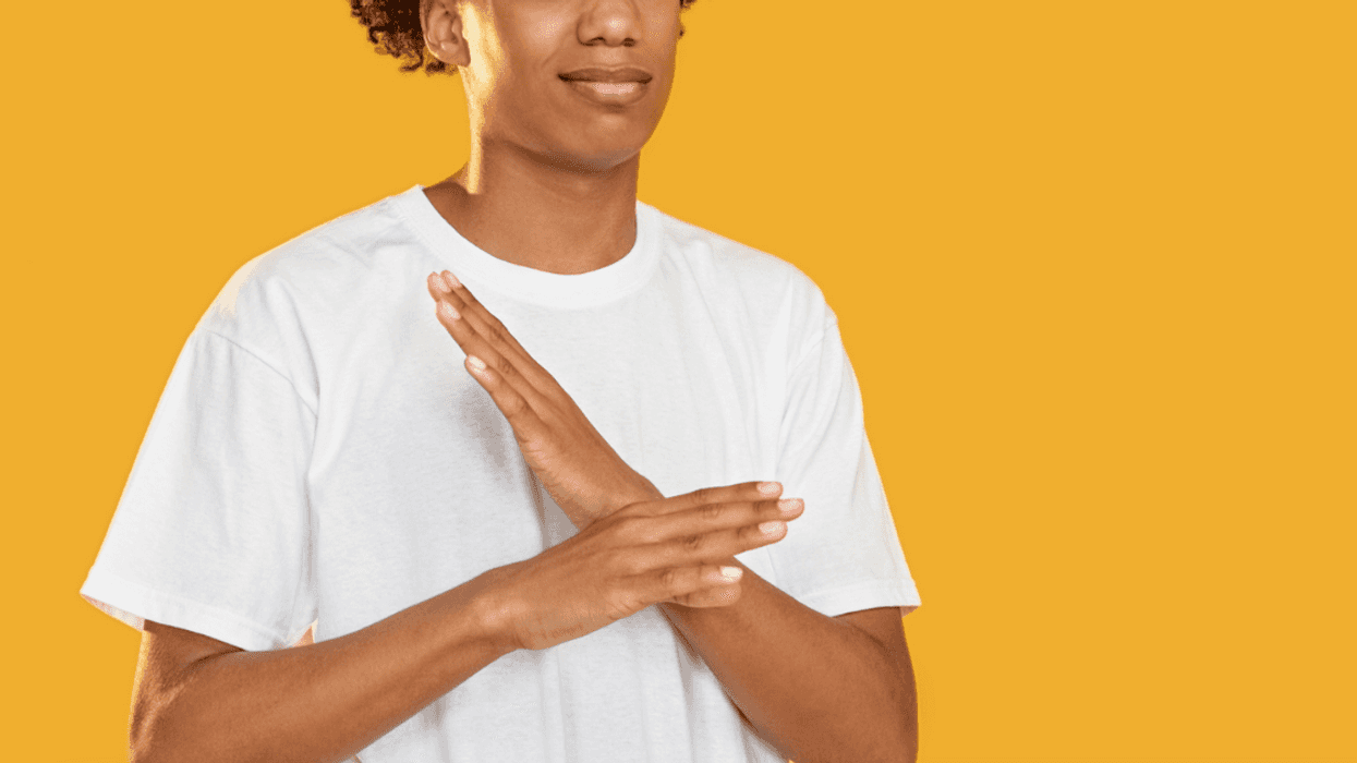 A man in front of a yellow background with his arms crossed.