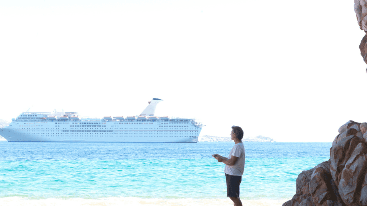 A man looking out at a cruise ship in thedistance.