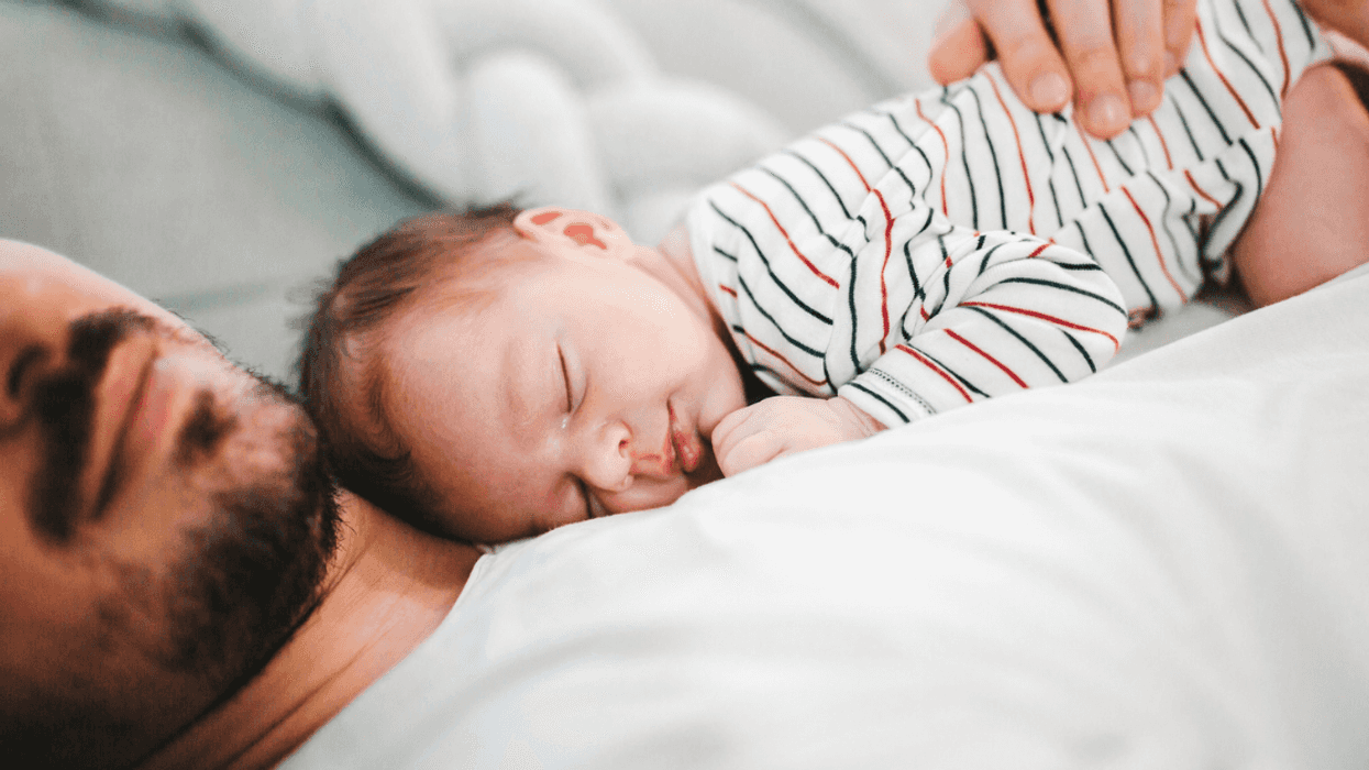 A man lying down with a baby lying on his chest.