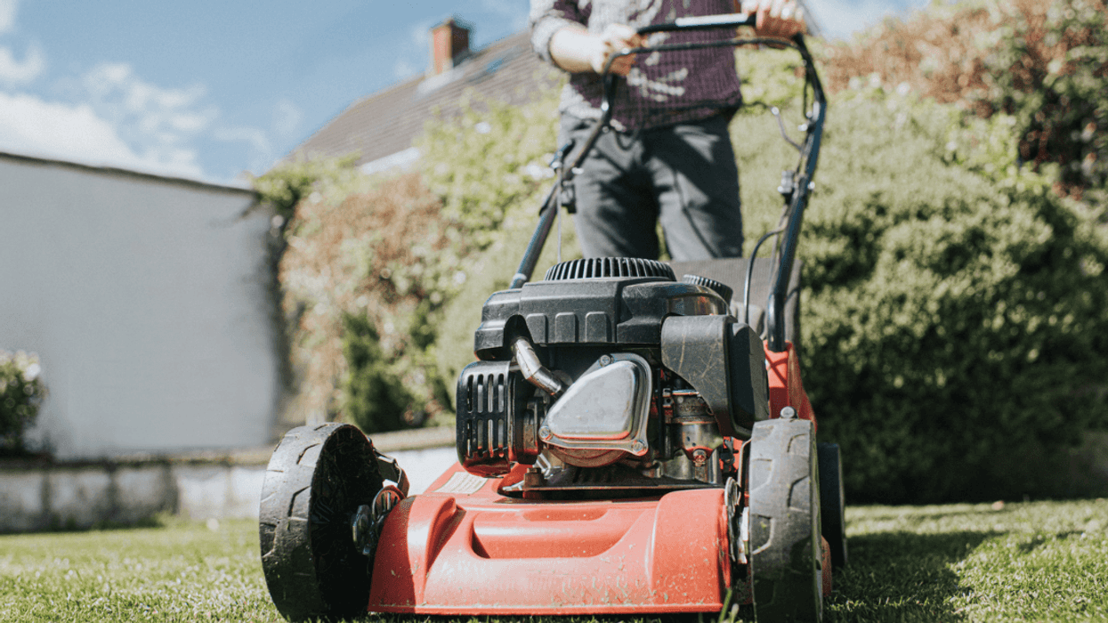 A man mowing a lawn with a lawnmower.