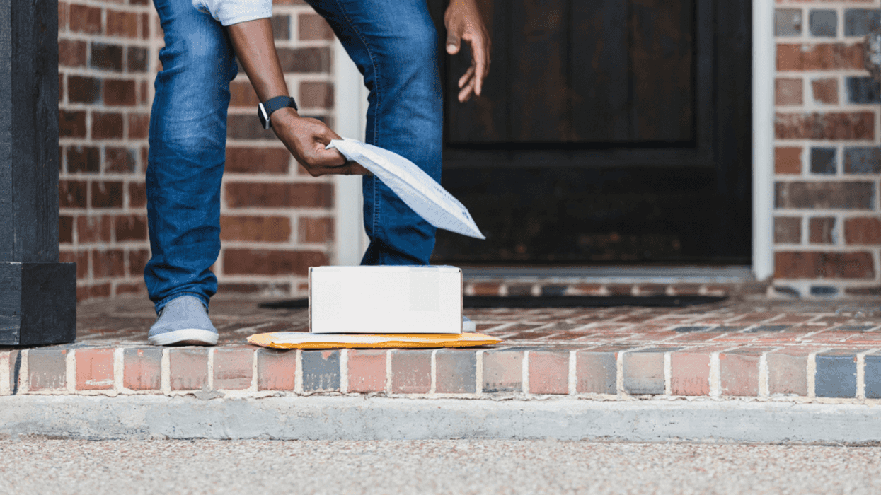 A man picking up packages on a doorstep.