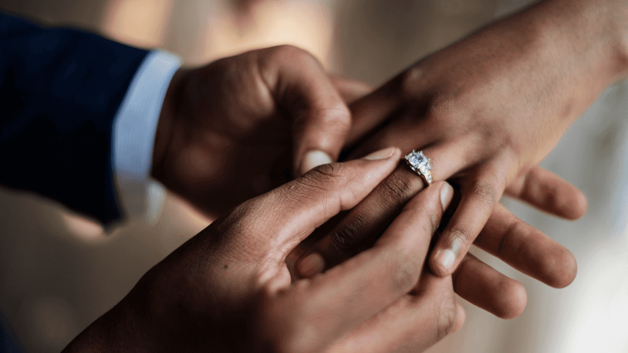 A man putting a ring on a woman's finger.