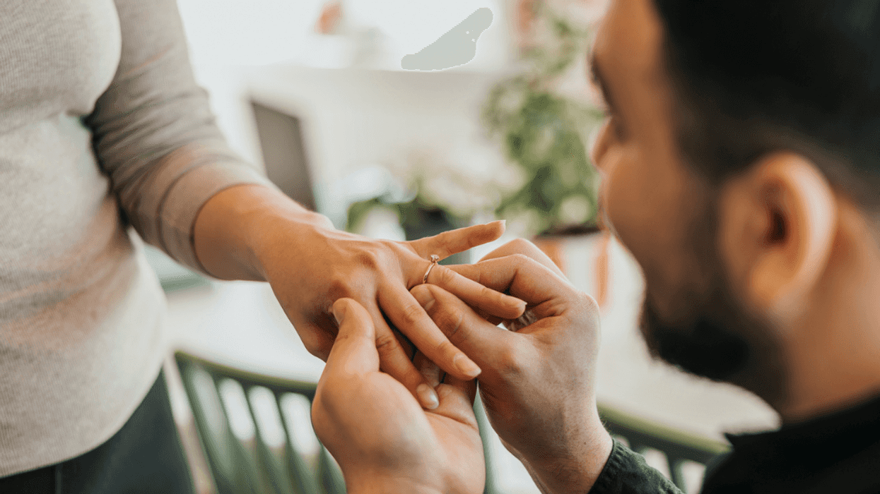 A Man putting a ring on a woman's finger.