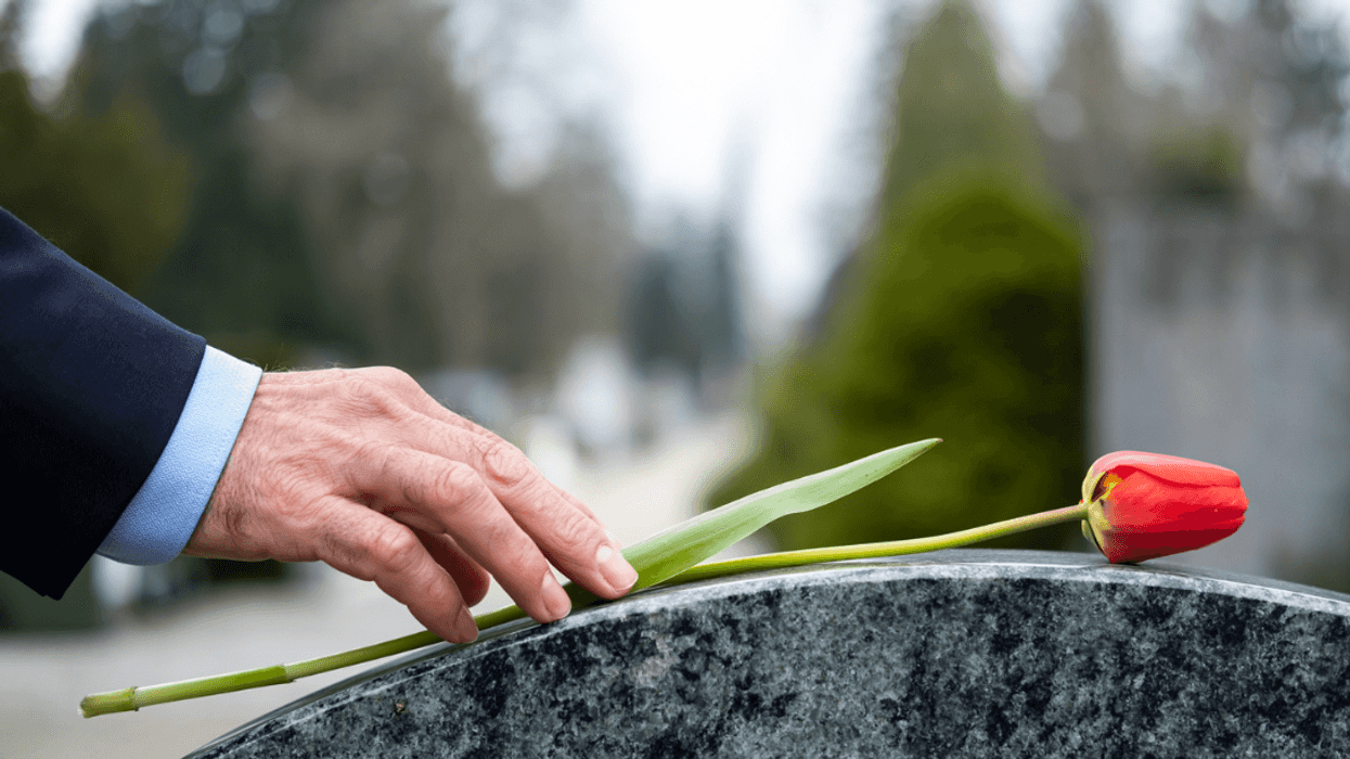 A man putting a rose on a grave.