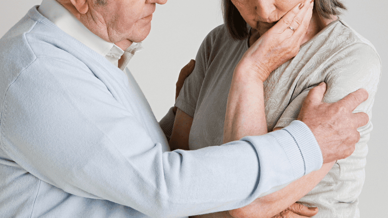 A man putting his arm around a woman with her head resting in her hand.