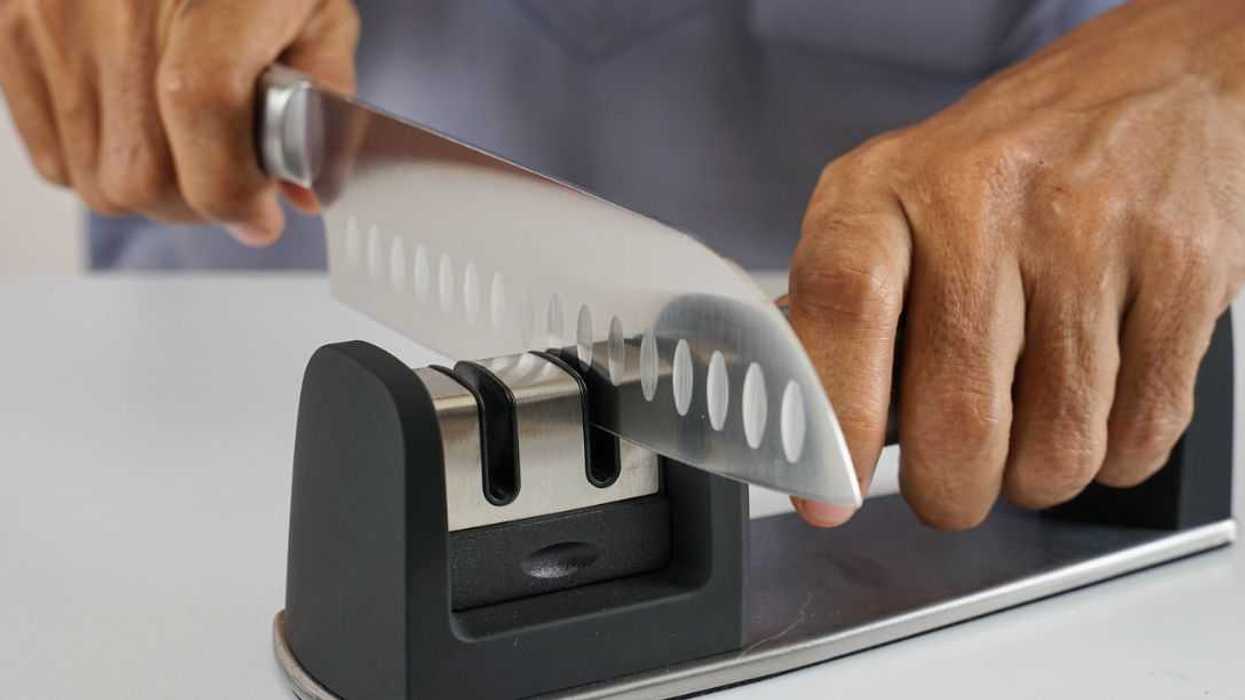 A man's hands sharpen a fancy kitchen knife.