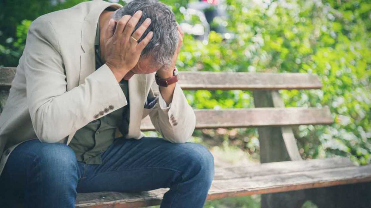 A man sits on a bench, head in his hands