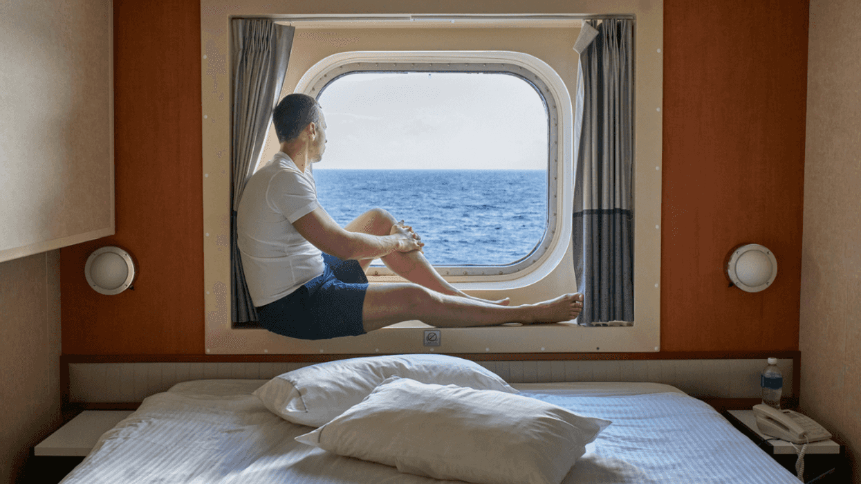 A man sitting at window in a cruise cabin.