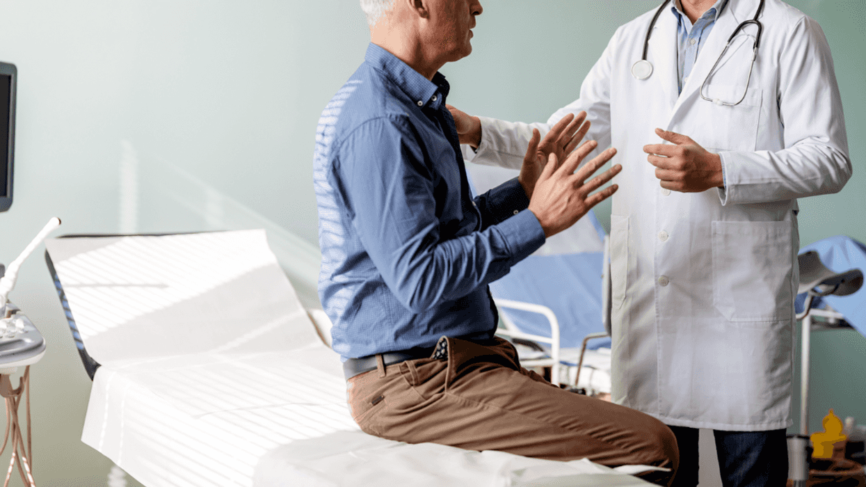 A. man sitting on an examination table talking to a doctor.