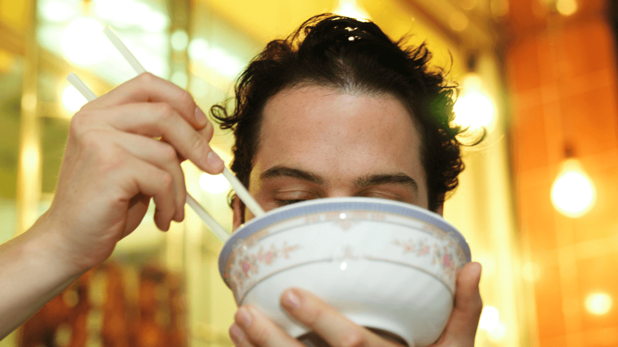 A man using chopsticks while eating rice.