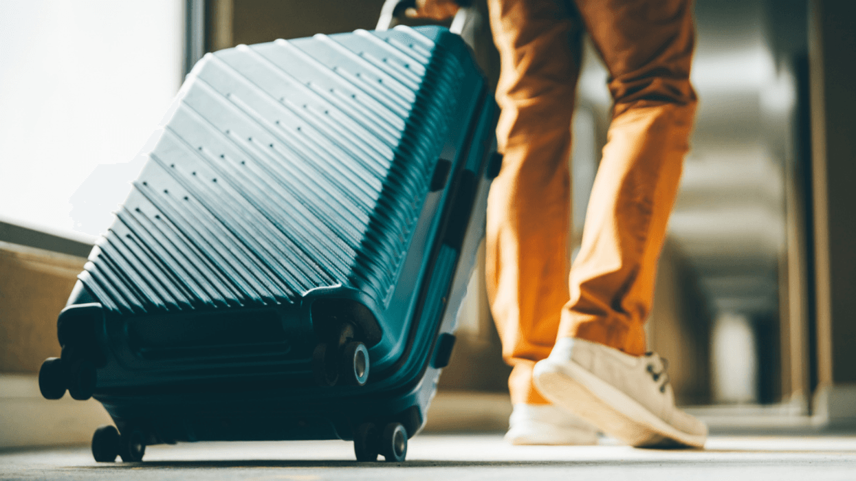 A man walking with a rolling suitcase