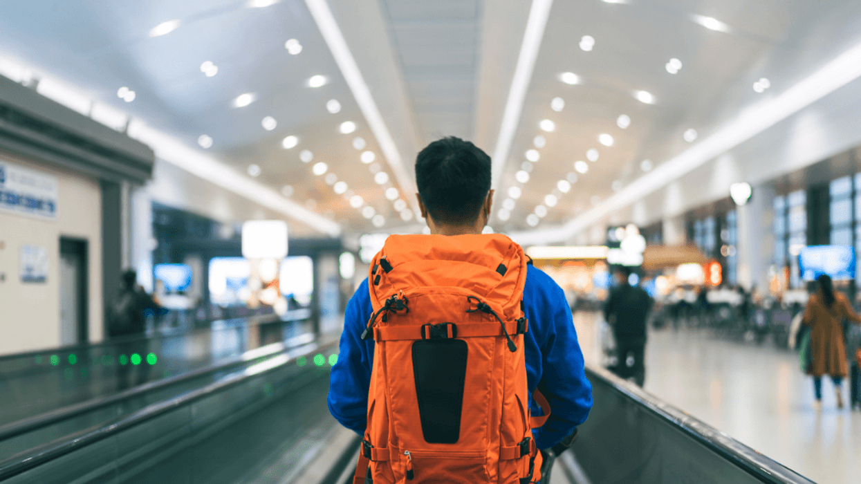 A man wearing a backpack in an airport.