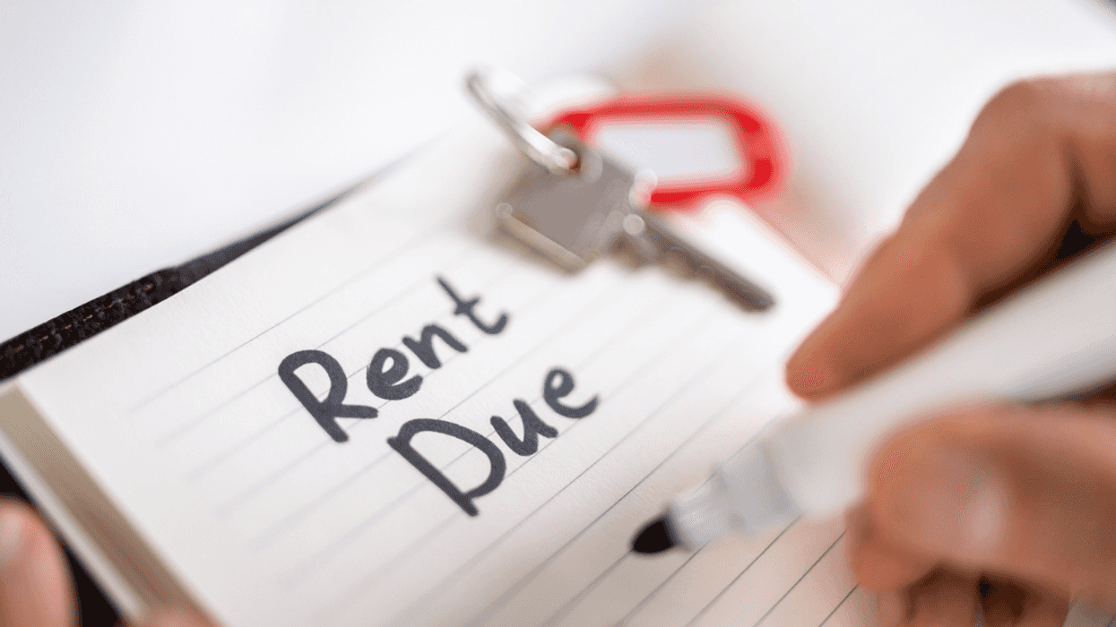 A man writing "Rent Due" on a pad of paper.