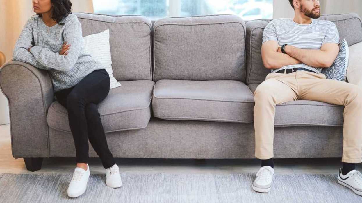 A mixed race couple sit across from one another on a couch, clearly not speaking