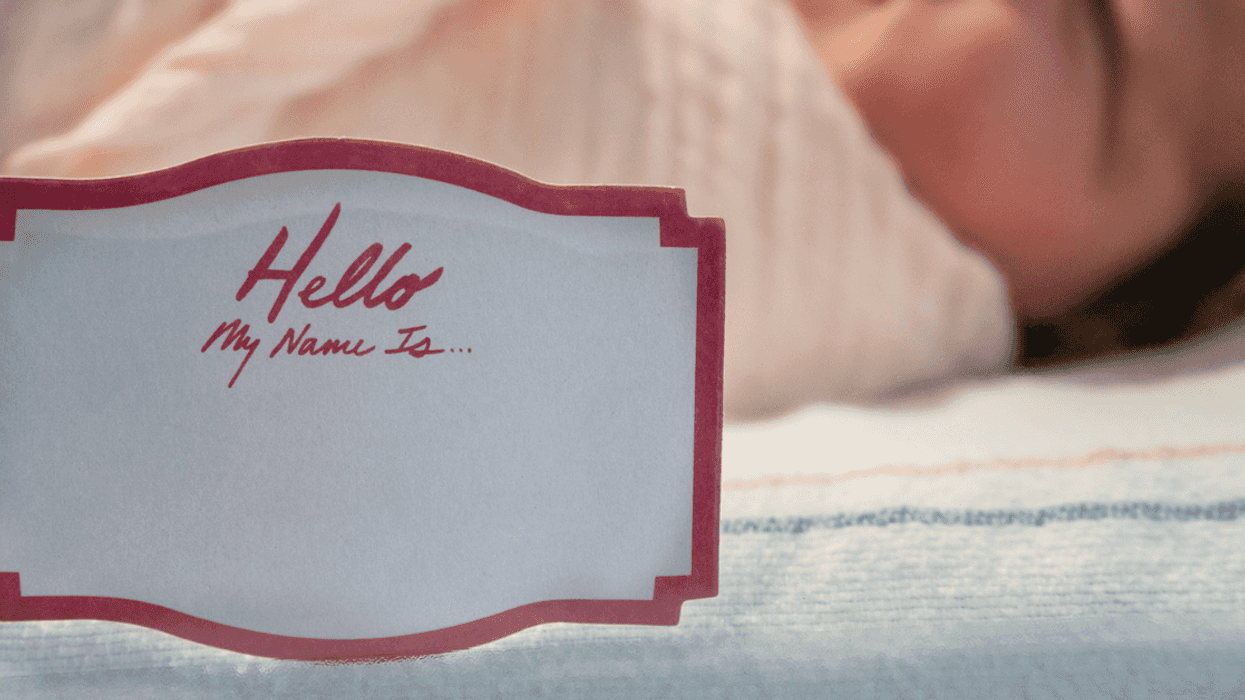 A Newborn baby in incubator with a name tag.