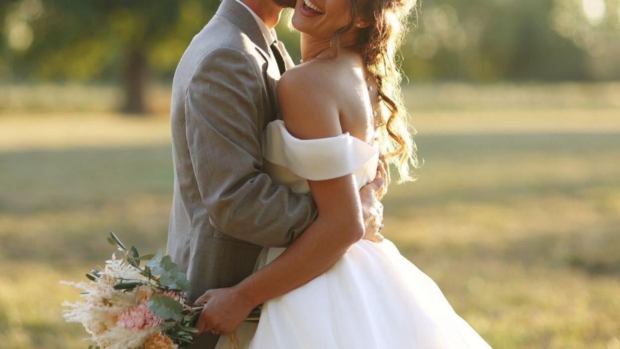 A newlywed couple posing together in the countryside.