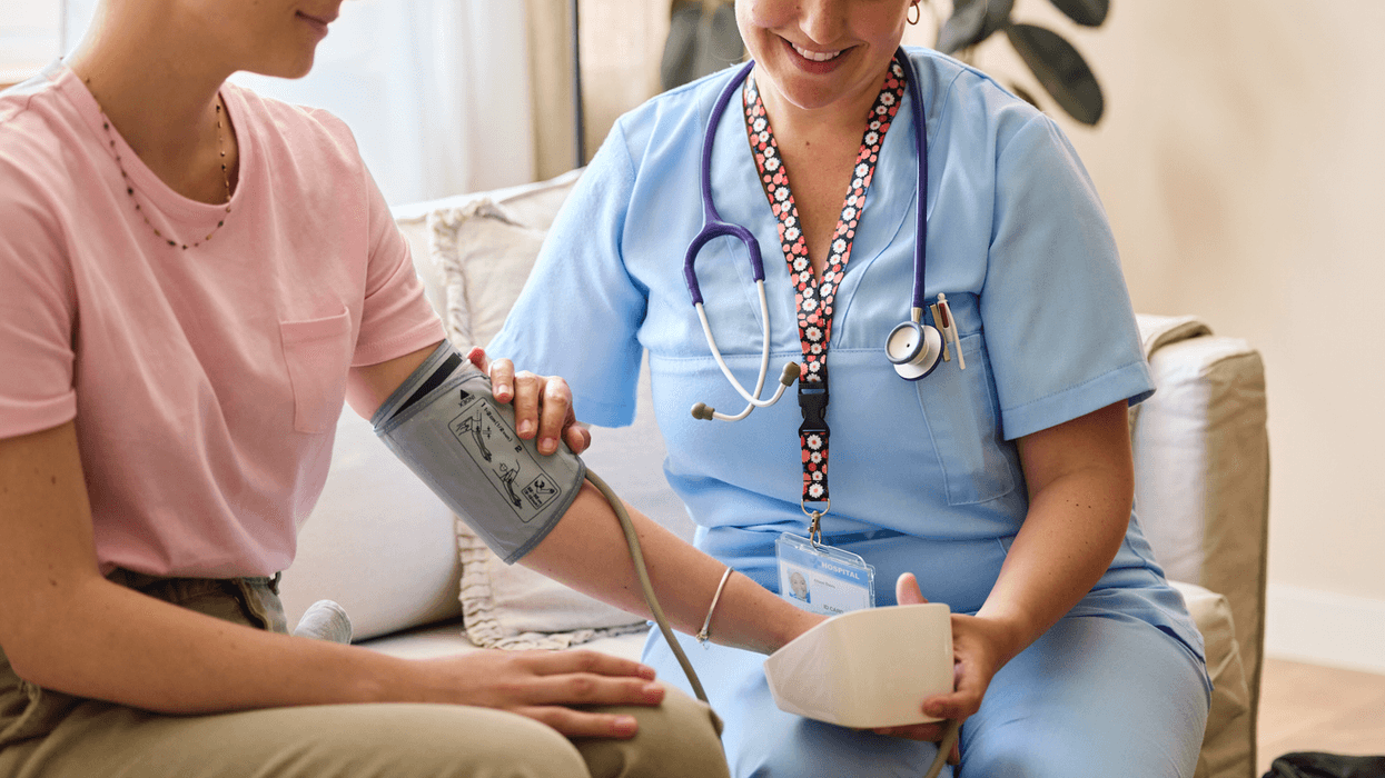 A nurse sitting next to a woman with a chemo IV in her arm.