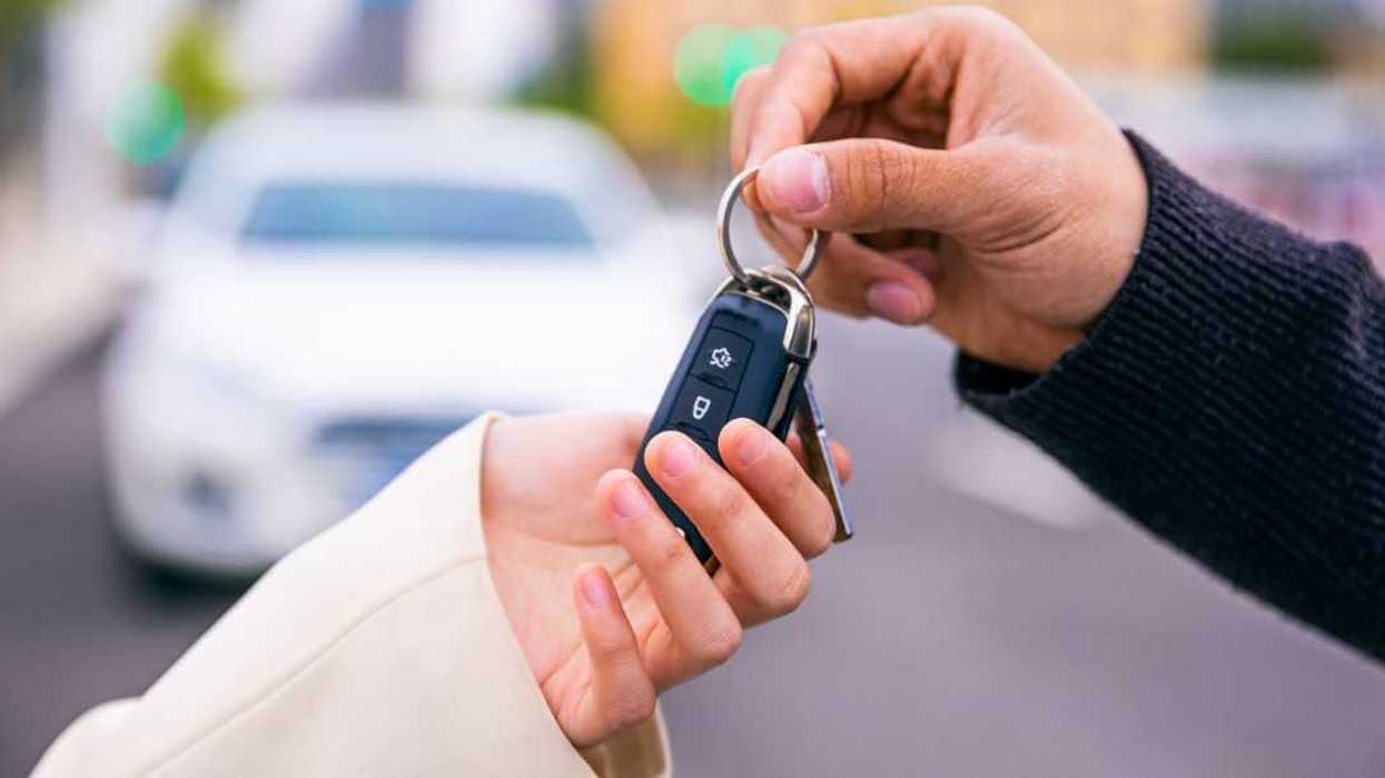 A pair of hands give a set of keys to another pair of hands.