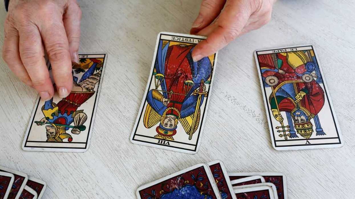 A pair of man's hands deals out tarot cards.