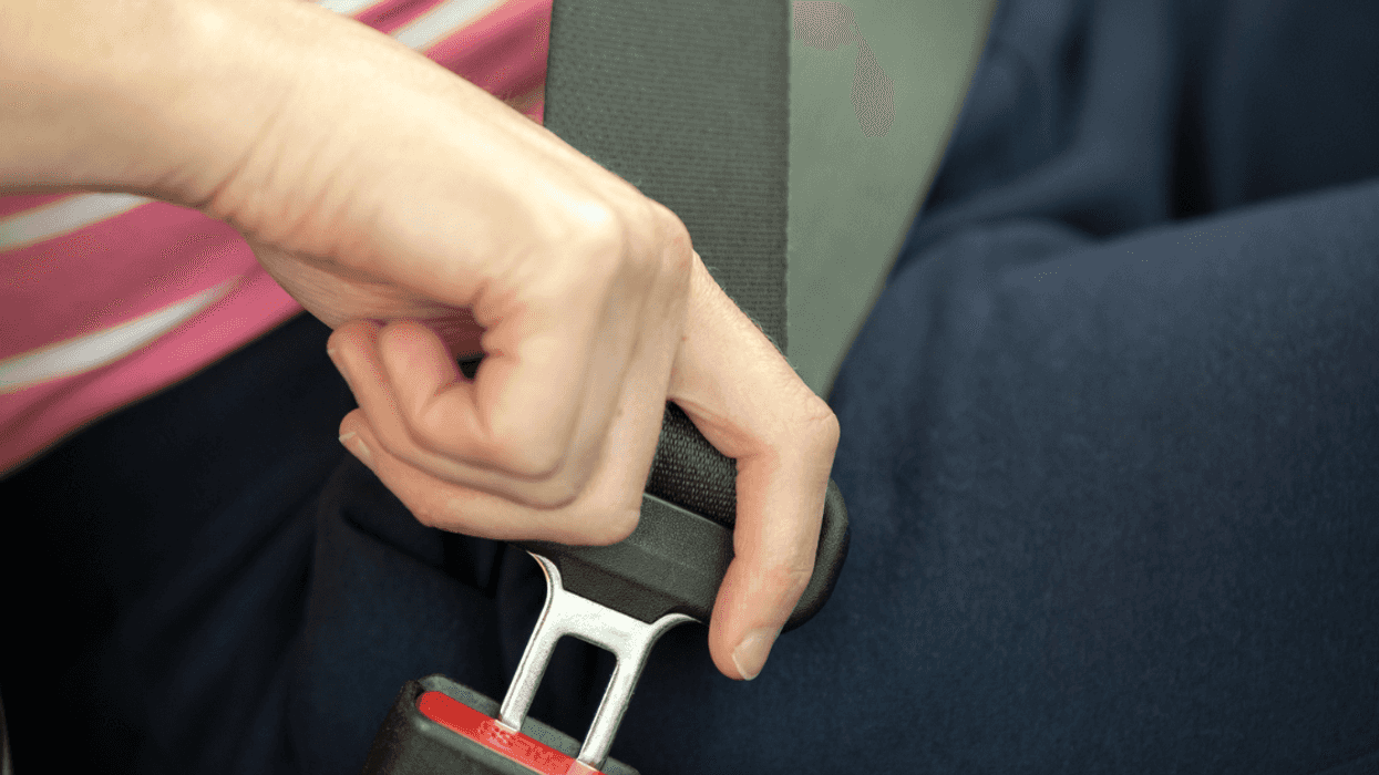 A person buckling their seatbelt.
