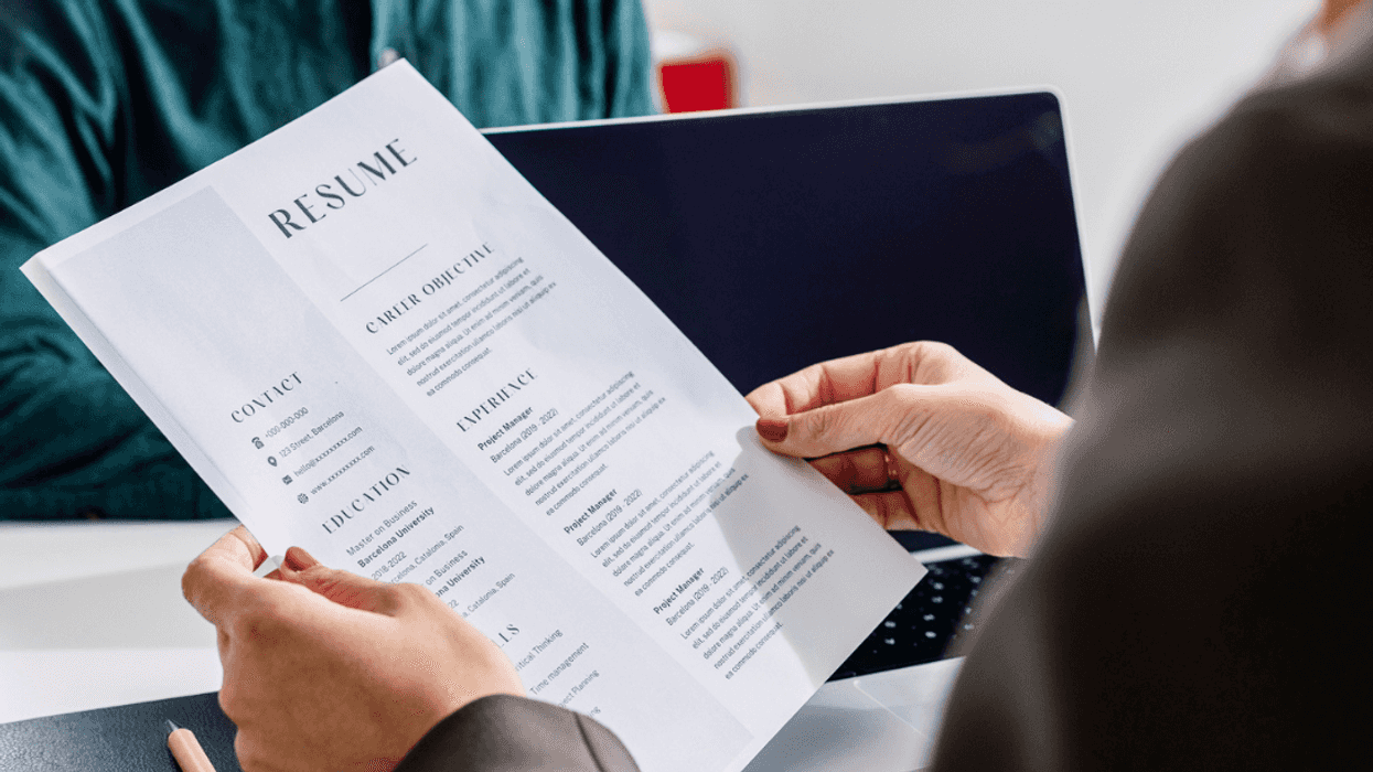 A person holding a resume with another person sitting across from them.