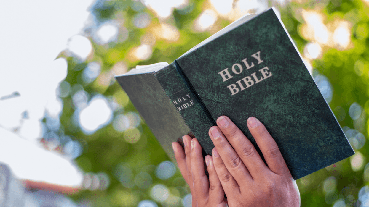 A person holding an open Bible.