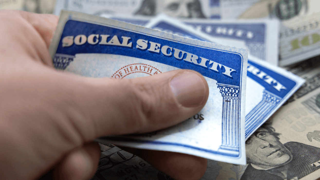 A person holding two social security cards over a pile of cash.