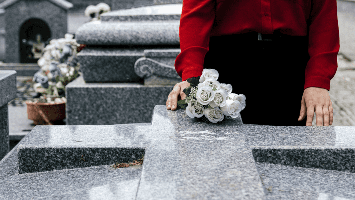 A person laying white flowers on a grave.