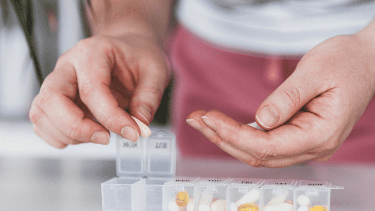 A person organizing pills into a daily pill box.