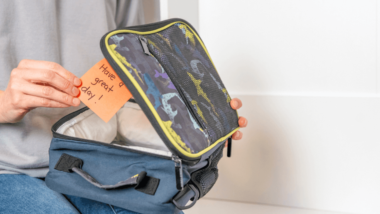 A person putting a note in a lunchbox.