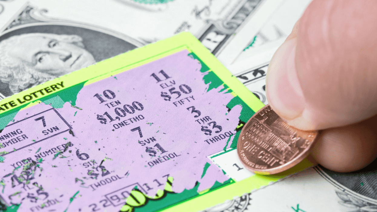 A person scratching off a lottery ticket with a penny.